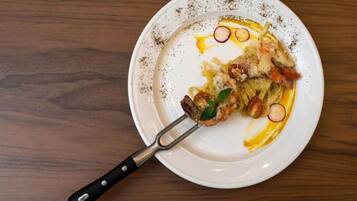 A white plate with remnants of food, including shrimp and vegetables, on a wooden table.