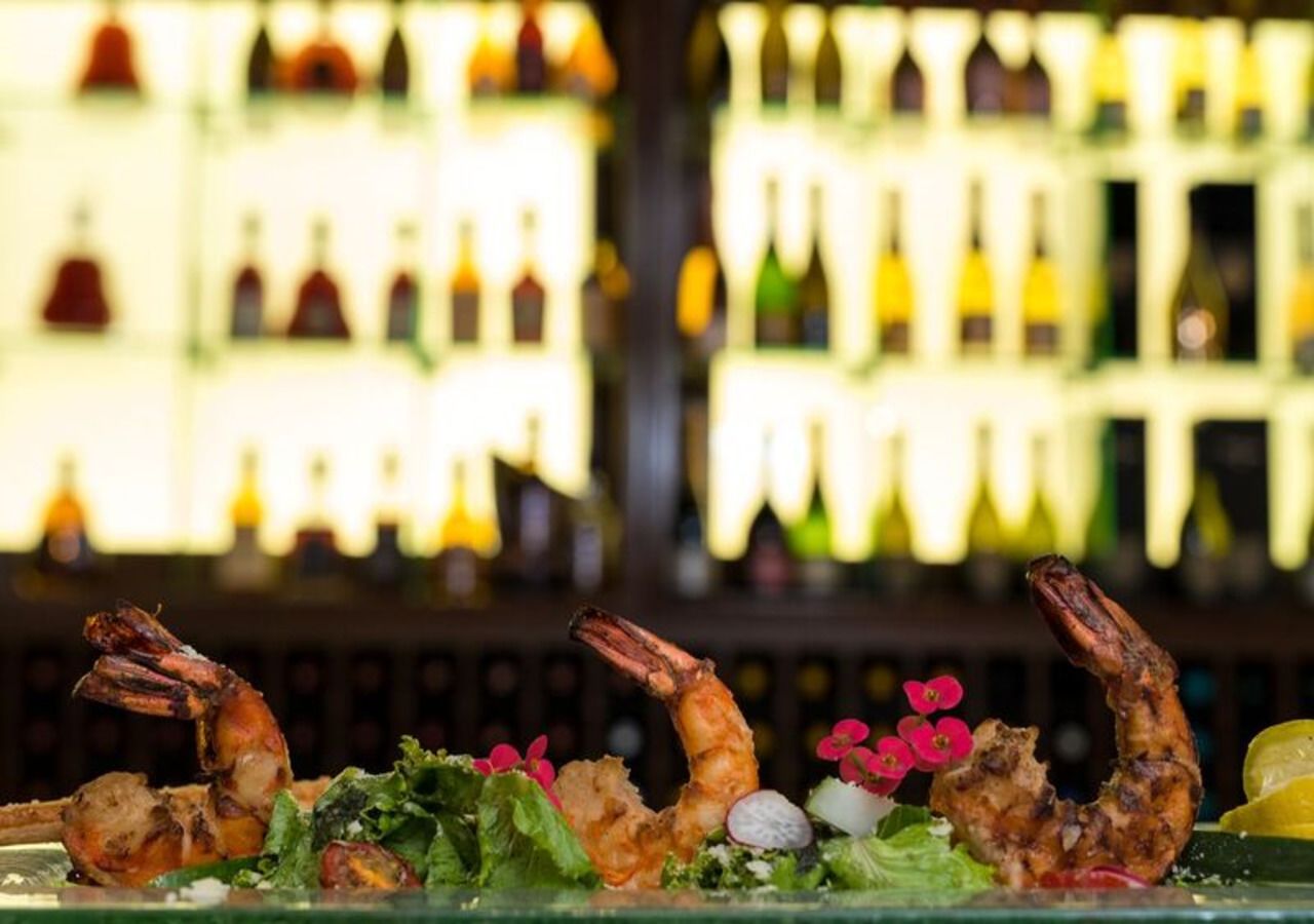 A seafood dish with shrimp and greens on a glass table.