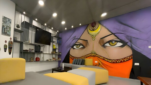 A modern living room with a large mural, a flat-screen TV, and a cozy seating area. - Nomads Hotel - Hostel (Amman)