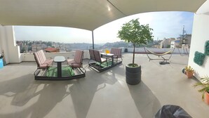 A rooftop terrace with a table and chairs, a hammock, and a potted tree. - Nomads Hotel - Hostel (Amman)