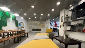 A modern interior with a long yellow bench, wooden tables, and a yellow sofa. - Nomads Hotel - Hostel (Amman)