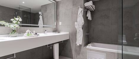 A modern bathroom with a large mirror, two sinks, a bathtub, and a glass shower enclosure.