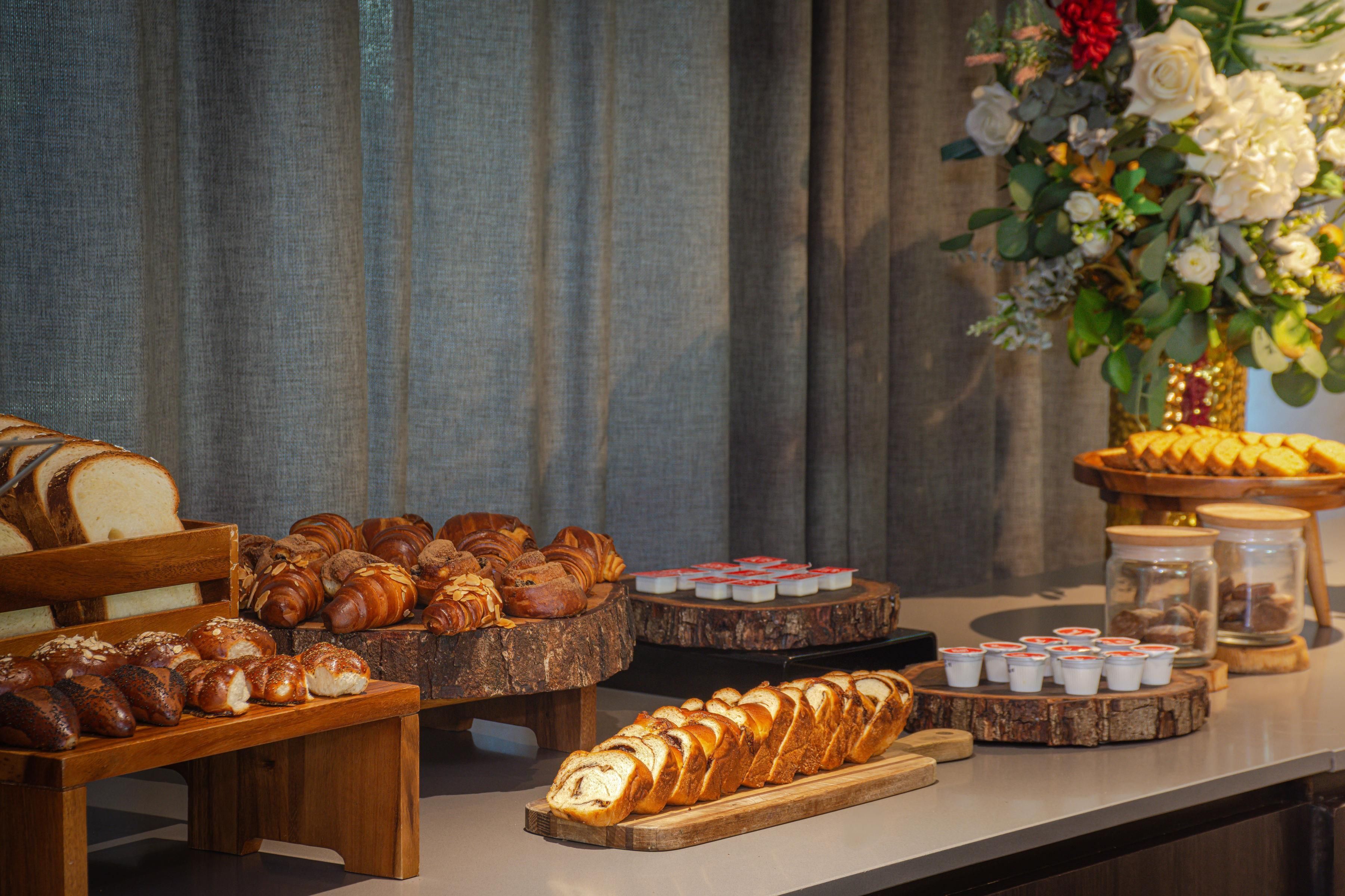 Une variété de pains et de viennoiseries présentés sur des présentoirs en bois et sur une planche en bois.