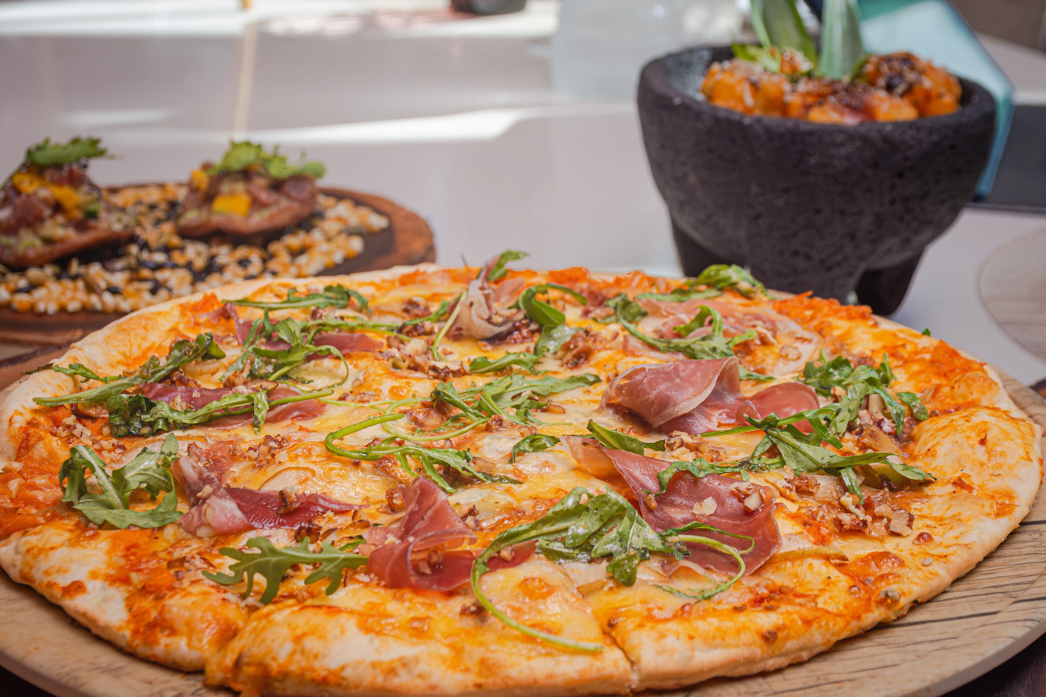 Una pizza con diversi condimenti su un tagliere di legno.