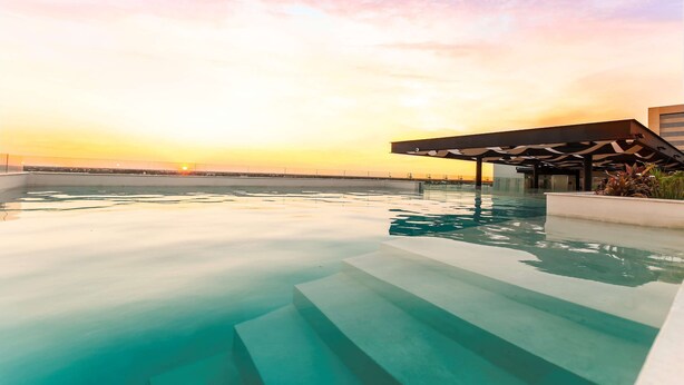 A rooftop infinity pool with clear water, steps leading down, and a sunset view. - NH Collection Merida Paseo Montejo (Mérida)