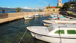 Un port de plaisance où sont amarrés plusieurs bateaux, un mur de pierre et, au fond, une église dotée d’un clocher.