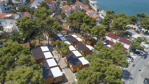 Vue aérienne d’un quartier résidentiel situé sur la côte, avec des rangées de maisons de plain-pied, dont certaines ont des toits recouverts de tuiles rouges, et une rue où sont garées des voitures.