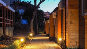 Un chemin menant à un bâtiment en bois, avec un sentier de gravier et de petites lumières disposées de part et d’autre.