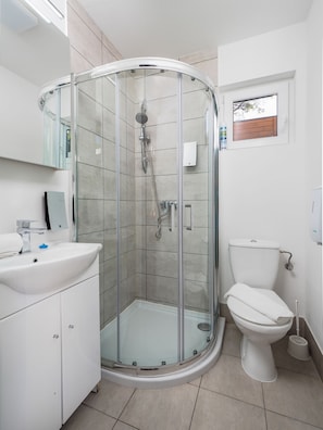 A modern bathroom with a glass-enclosed shower, a white sink, and a toilet. - Mediteran Travel Camping Sveti Križ (Trogir)