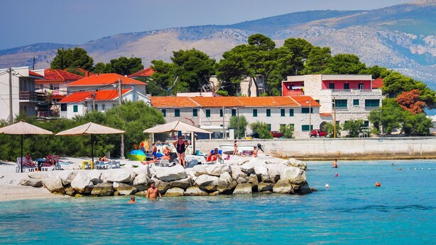 Une zone côtière caractérisée par une côte rocheuse, des parasols de plage et des personnes profitant de la mer.