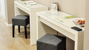Una habitación con dos escritorios blancos, cada uno con un taburete tapizado en gris. Encima de los escritorios, decoración de pared de piedra.