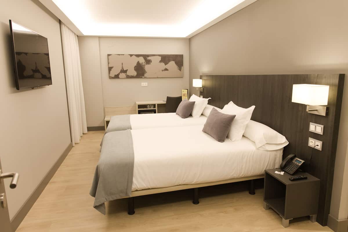 Habitación de hotel con una cama grande, lámparas de noche, un televisor de pantalla plana y un escritorio con silla.