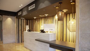 Een modern ontworpen receptiegedeelte, met een receptiebalie, een wandlamp en een hangende lamp.