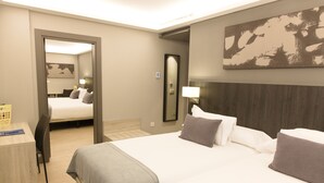Een hotelkamer met een groot bed, een bureau en een stoel. Er is een spiegel aan de muur en een schilderij boven het bed.