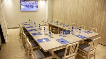 A conference room with a long table, chairs, water bottles, nameplates, and a television screen on the wall.