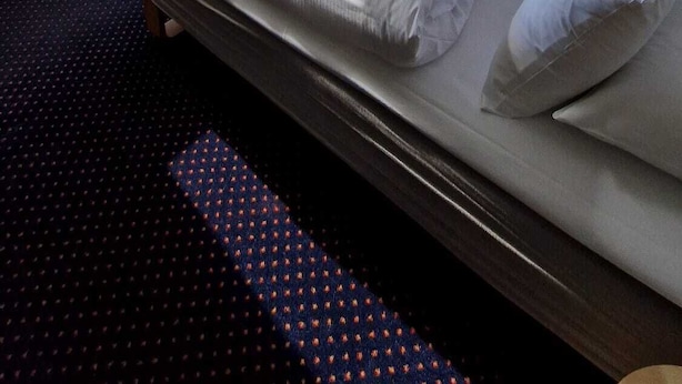 A hotel room with a large bed, a small table, a chair, and a view of a lake and mountains. - Sognefjord Hotel (Sogndal)