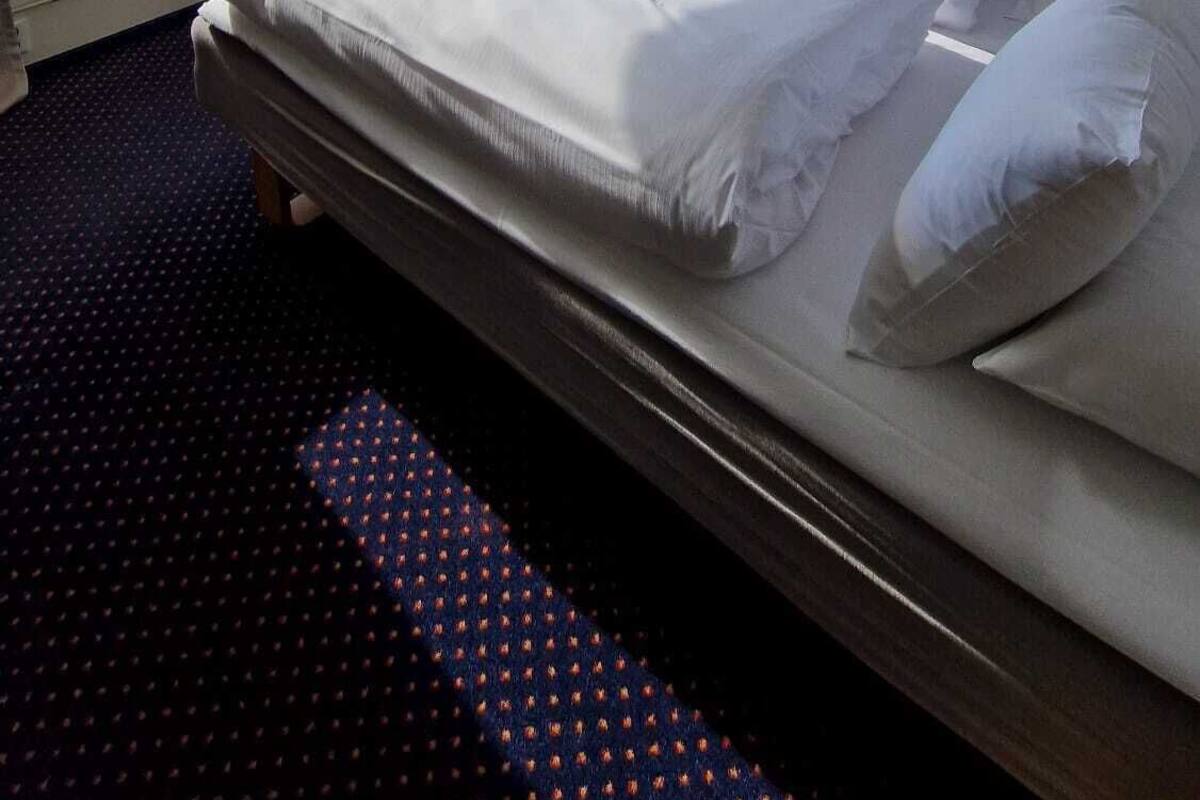 Habitación de hotel con una cama grande, una mesita, una silla y vistas a un lago y montañas.