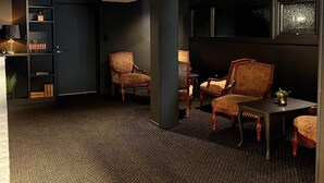 A room with a dark carpet, wooden chairs, a small table, and a bookshelf. - Sognefjord Hotel (Sogndal)