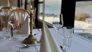 A table set for dining with a candle, glasses, and cutlery, overlooking a scenic view. - Sognefjord Hotel (Sogndal)
