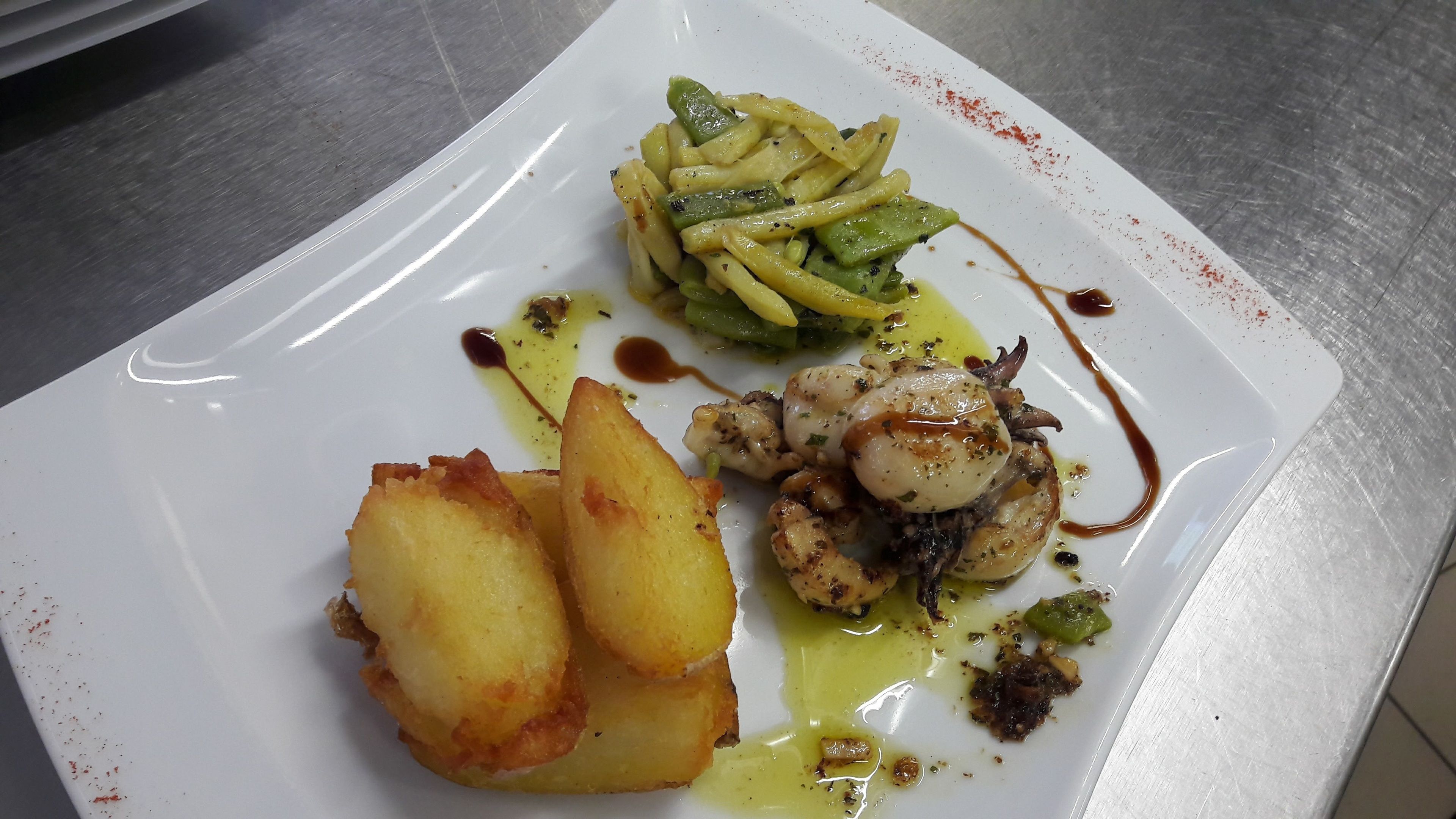 Une assiette blanche contenant divers aliments, notamment desSaint-Jacques, des pommes de terre et des légumes verts, le tout agrémenté de sauces.