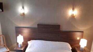 Een hotelkamer met een bed, twee nachtkastjes met lampen, een stoel en een wandlamp.