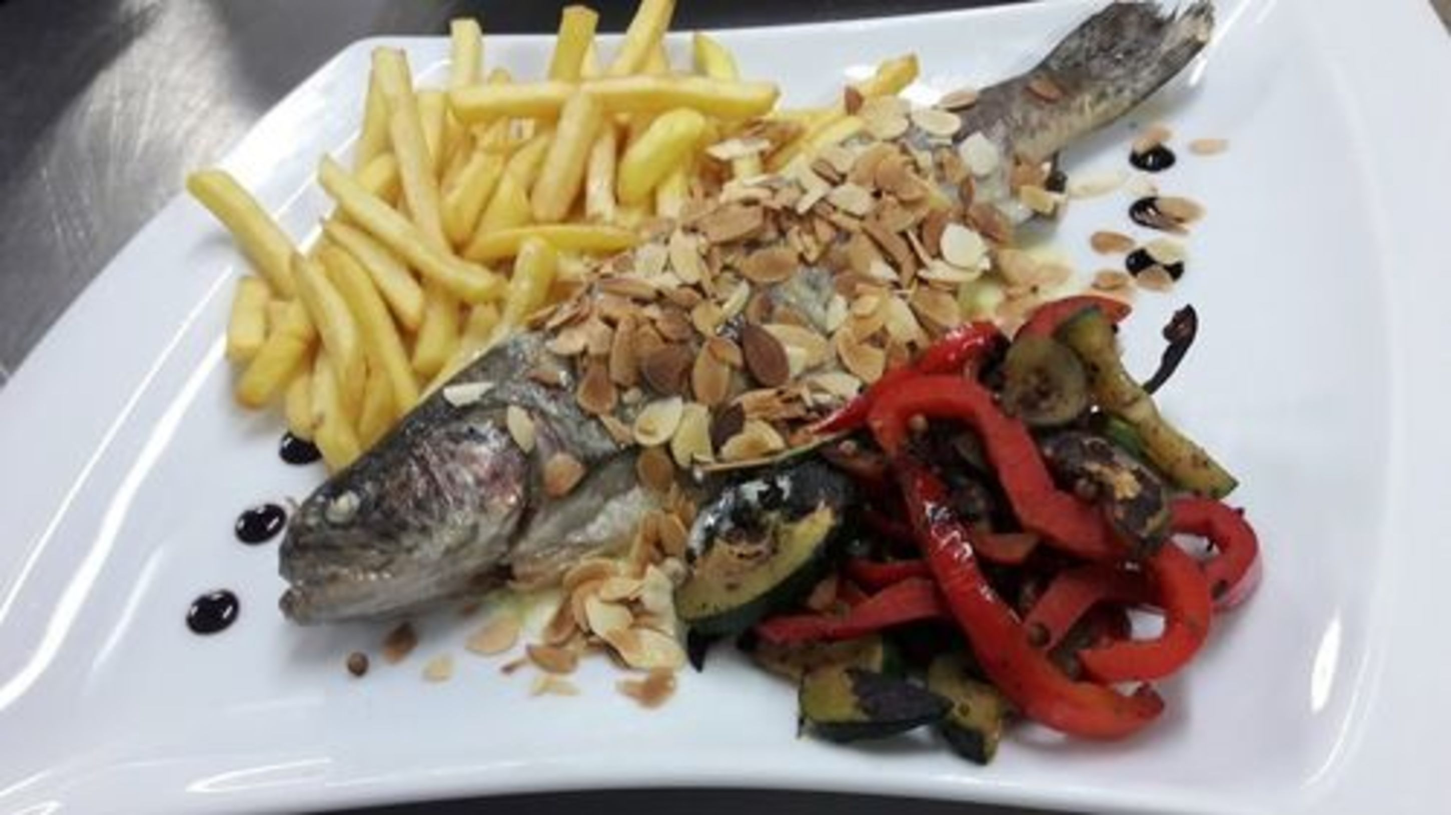 Een bord met vis, friet en geroosterde groenten.