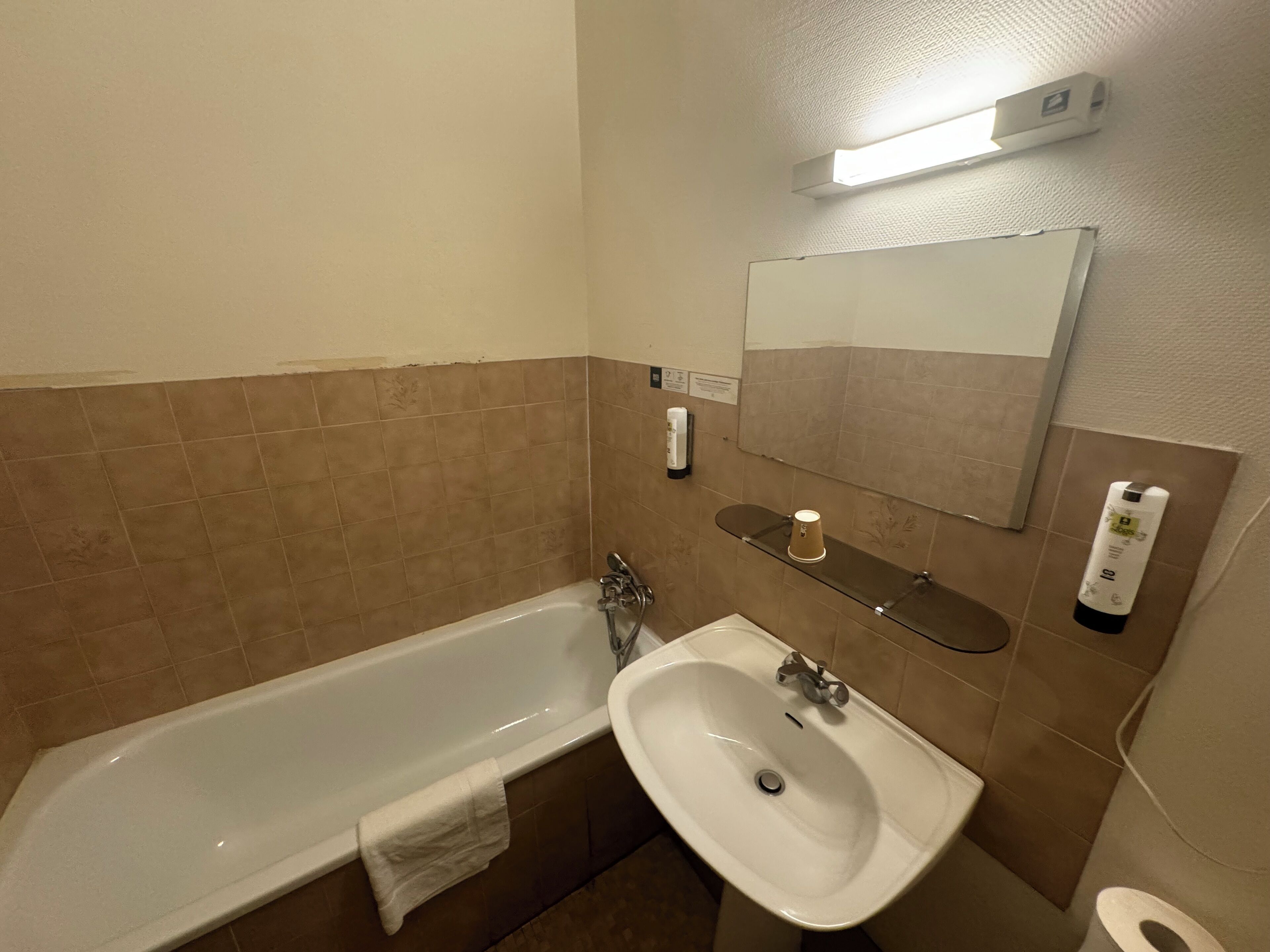 Ein Badezimmer mit einer Badewanne, einem Waschbecken, einem Spiegel und einem Ablagefach mit Pflegeprodukten.