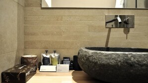 A bathroom with a large stone sink, a mirror, and toiletries on the counter. - Olivia Rooms Eurialo (Syracuse)