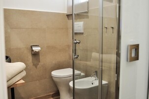 A modern bathroom with a glass shower enclosure, a toilet, and a sink.