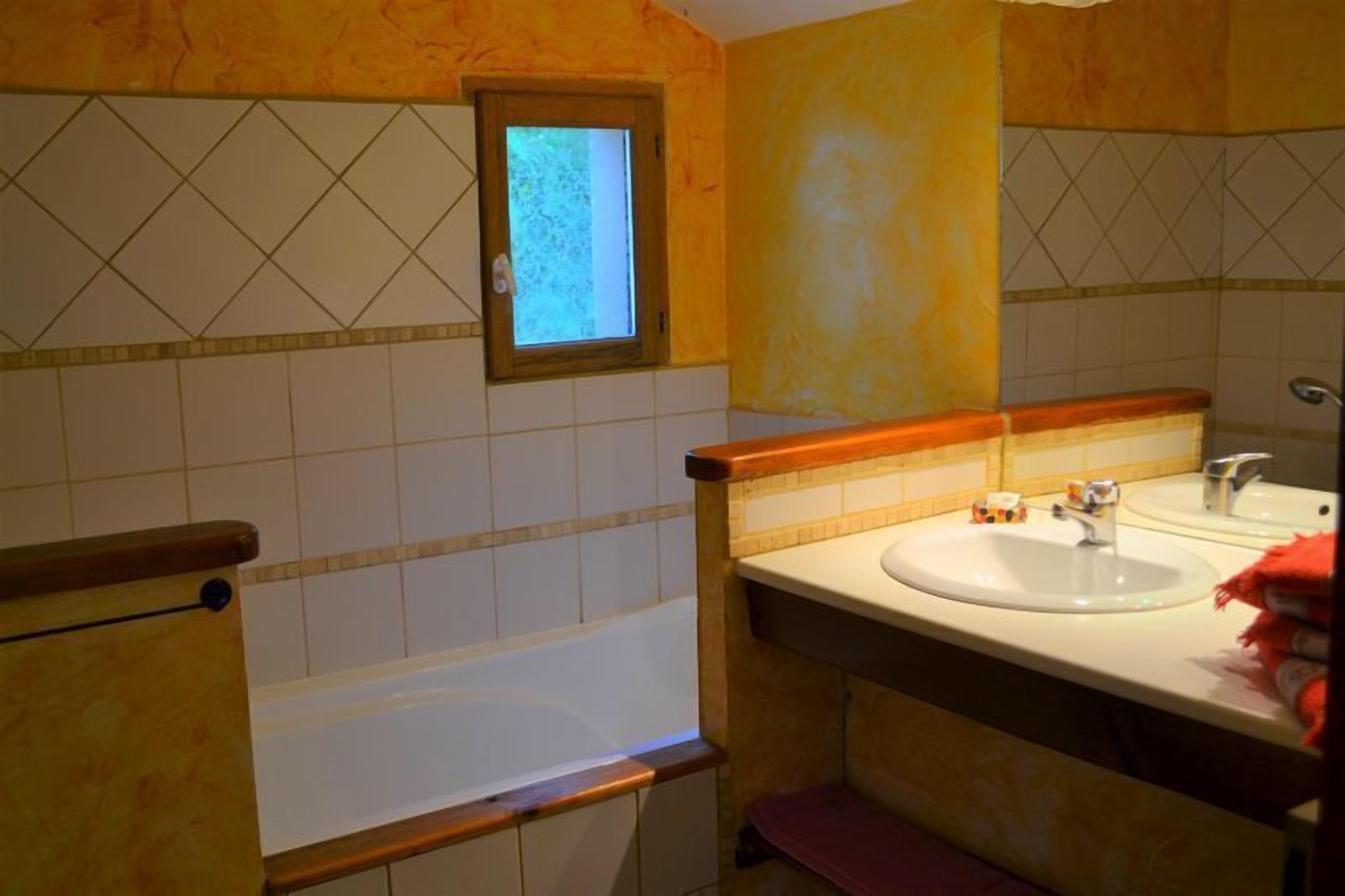 A bathroom with a bathtub, a sink, and a window.
