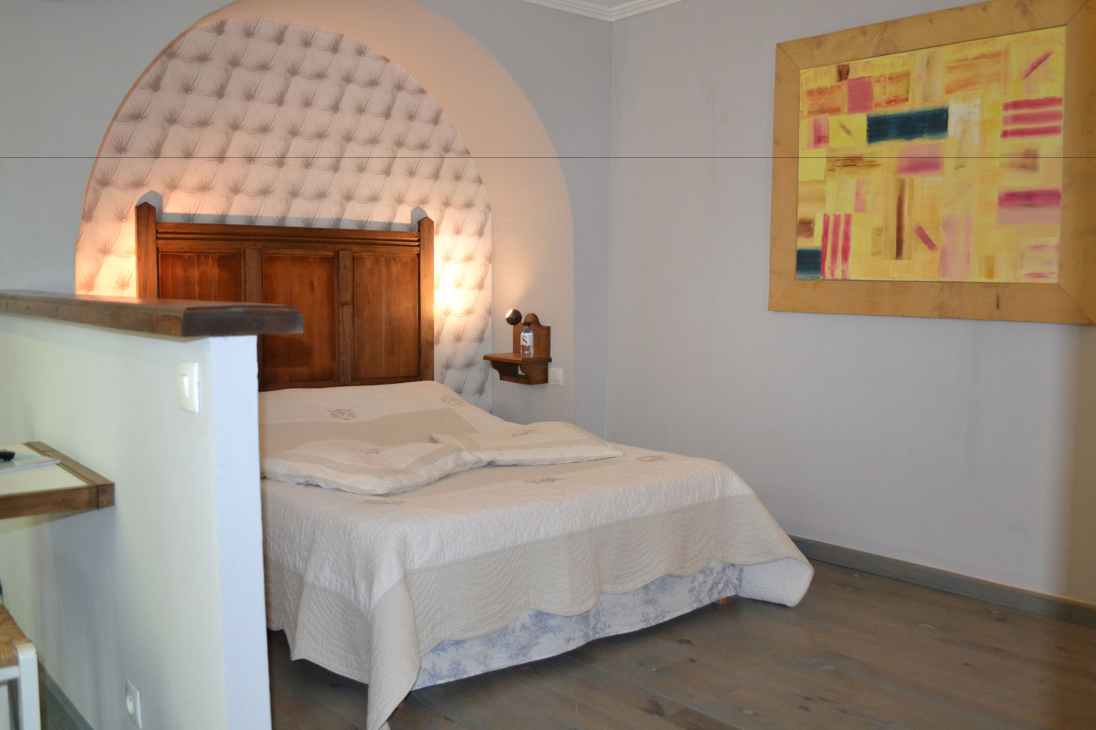 Ein Schlafzimmer mit einem Bett, einem Holzkopfende, einem Wandbild und einem kleinen Nachttisch.