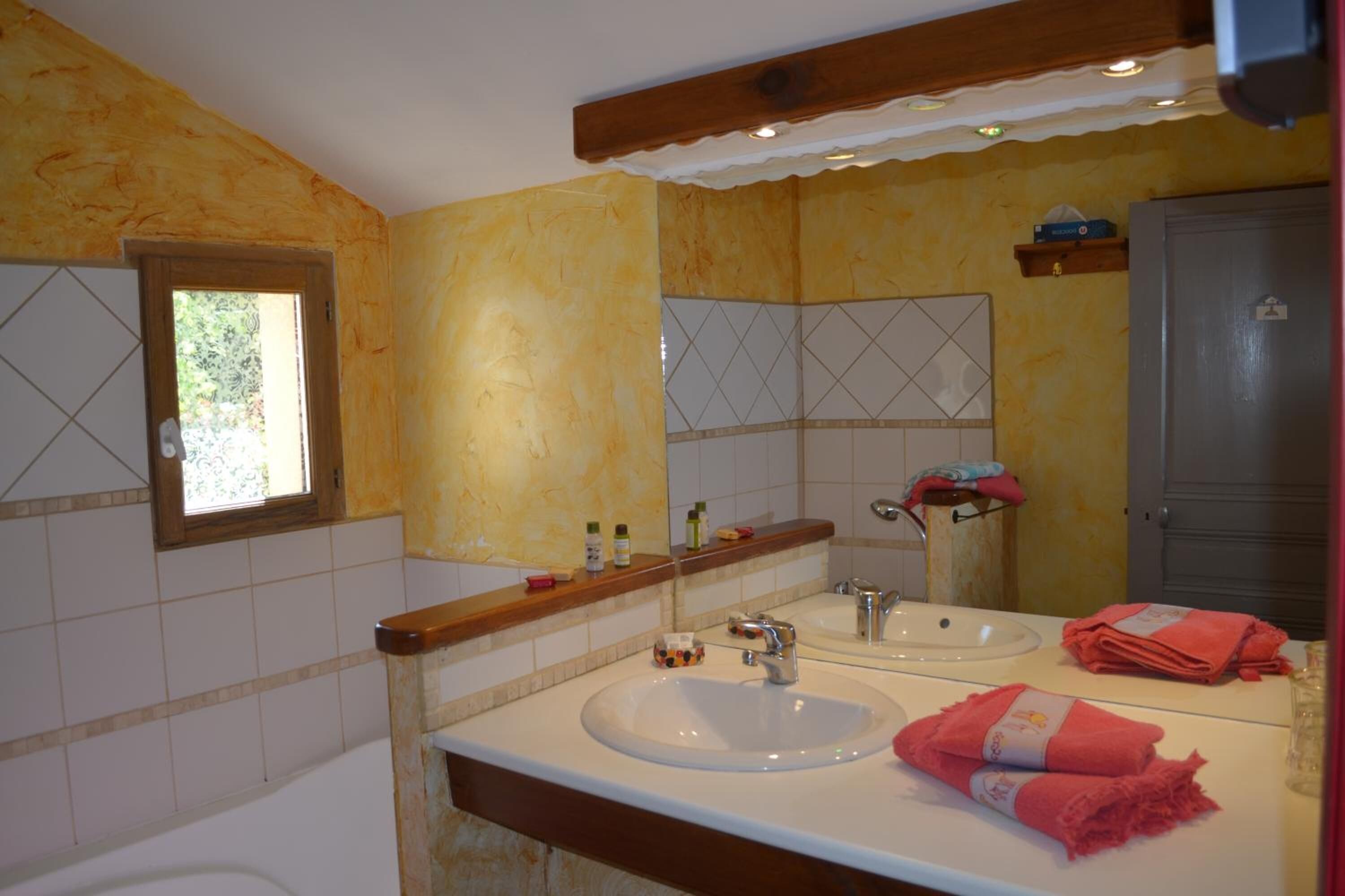 Casa de banho com duas pias, uma janela e um espelho.