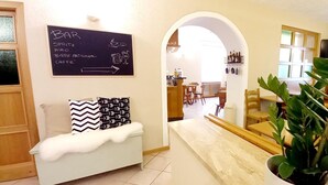 A cozy interior with a sofa, a chalkboard menu, and a dining area visible through an archway.