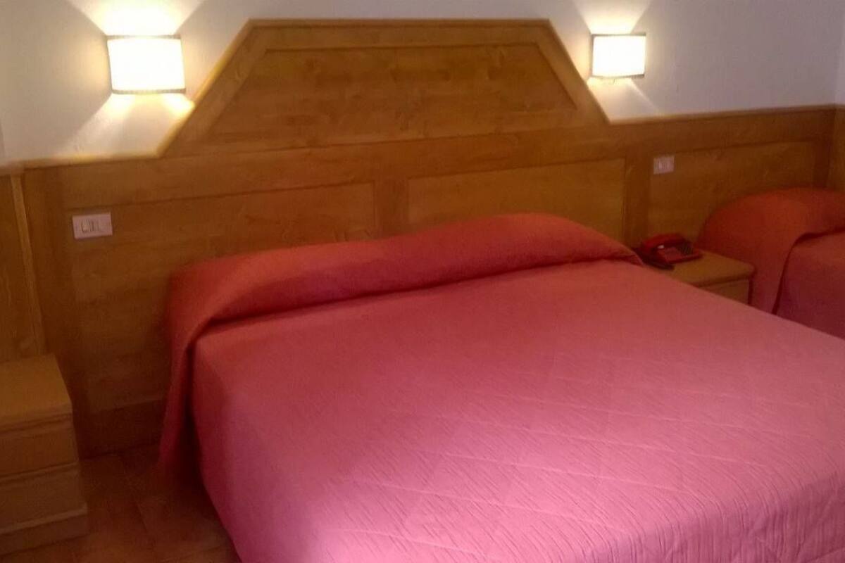 Een kamer met twee bedden, houten hoofdeinden en bedlampjes.