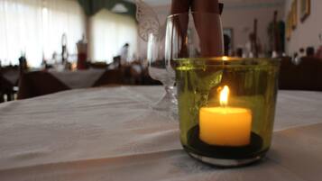 A candle in a glass holder on a table with a white tablecloth.