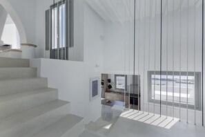 Un interior moderno con una escalera que lleva a un comedor, una cocina con vistas y un gran ventanal.