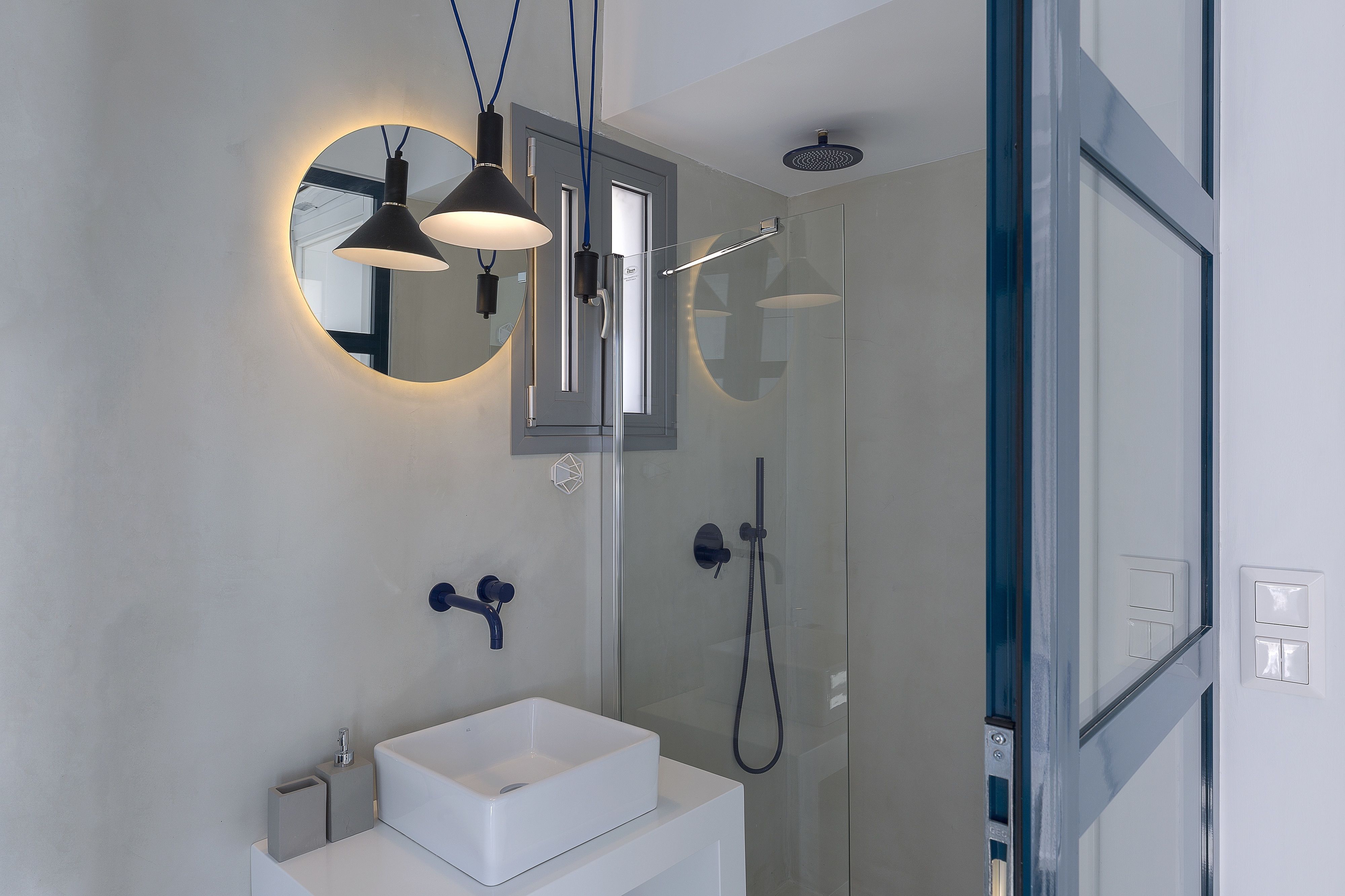 A modern bathroom with a white sink, a mirror, and a glass-enclosed shower.