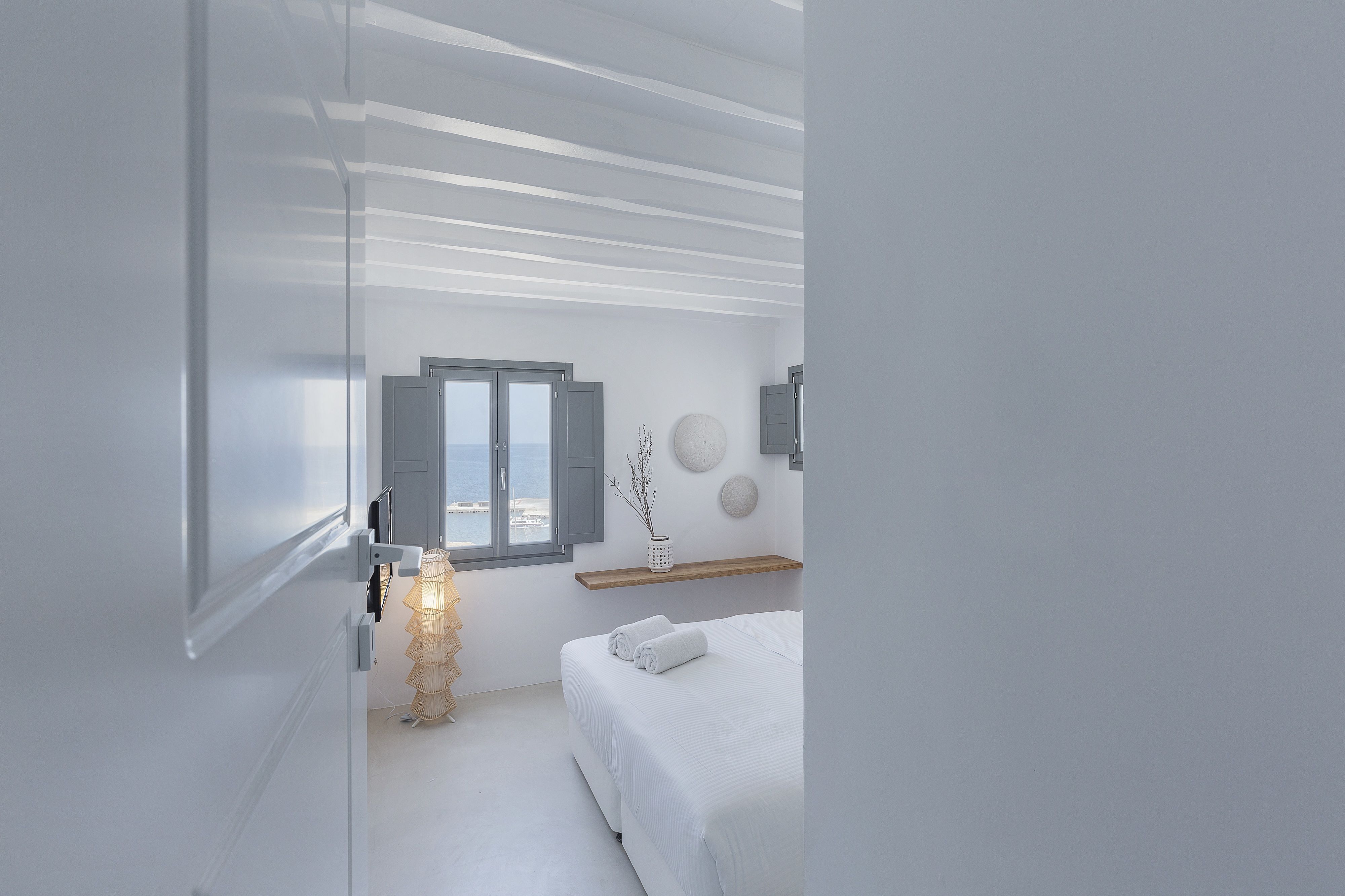 Ein modernes Schlafzimmer mit Bett, Fenster und einer Wandablage.