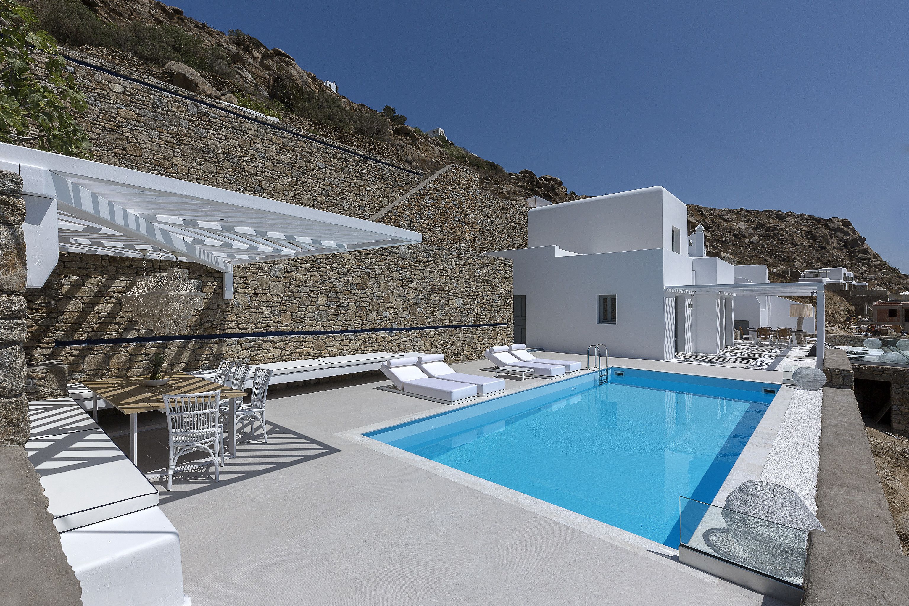 A modern outdoor pool area with white lounge chairs and a pergola.
