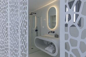 Un baño moderno con una bañera independiente, un espejo grande y un box de ducha.