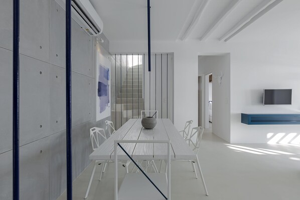 A modern conference room with a white table, chairs, and a TV on the wall.