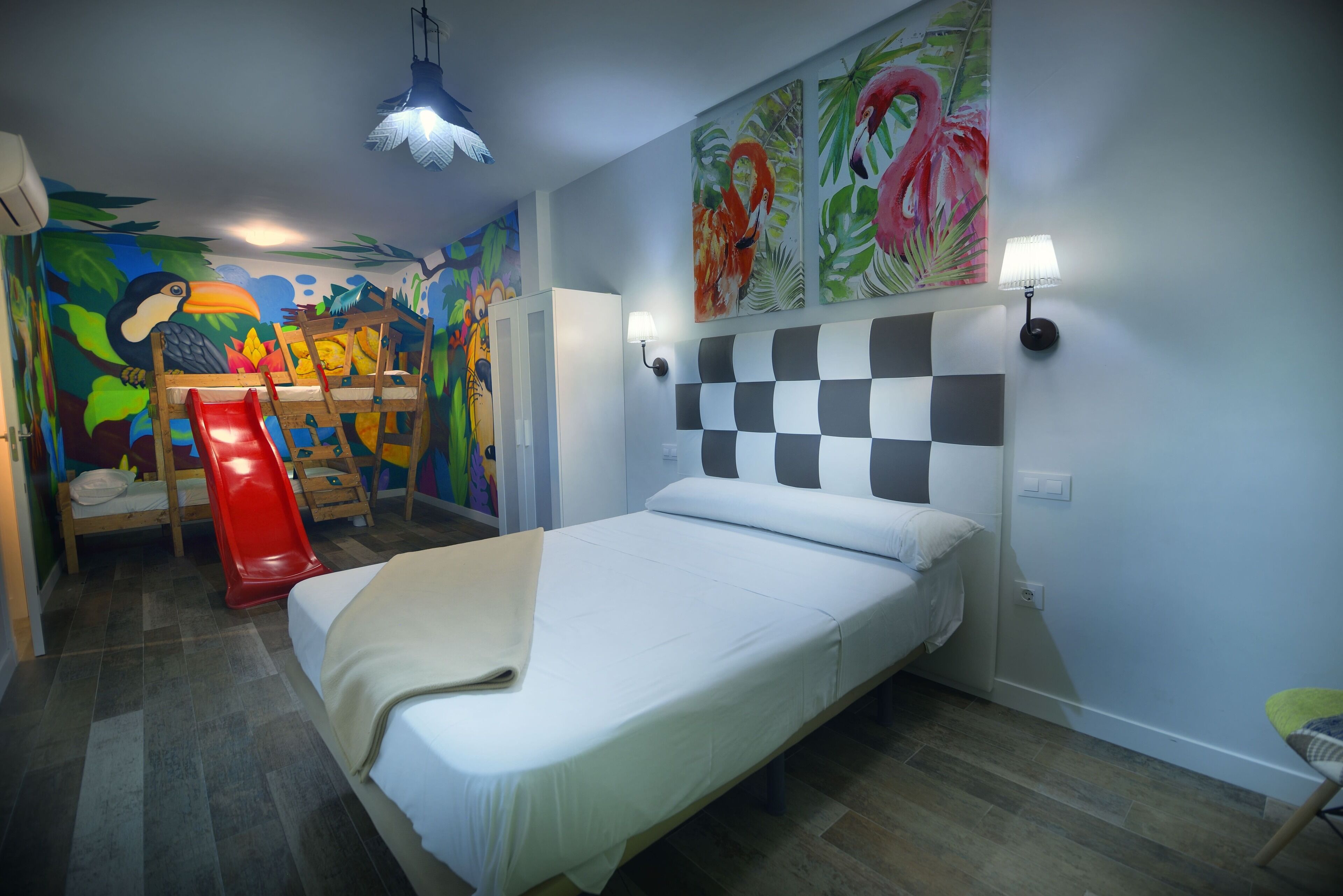A bedroom with a bed, a red slide, and colorful murals on the walls.