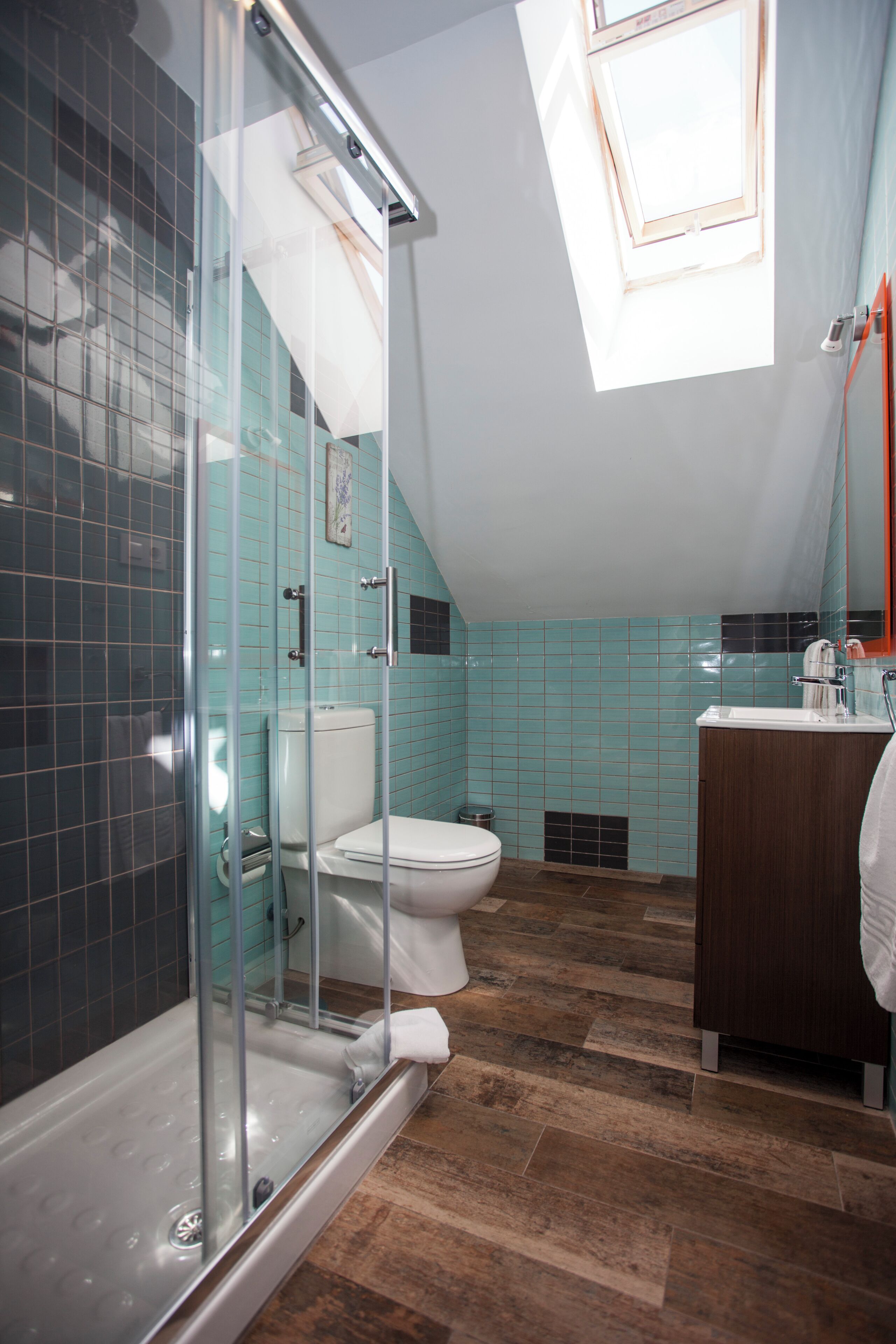 Een badkamer met een douchecabine van glas, toilet, wastafel en een raam.