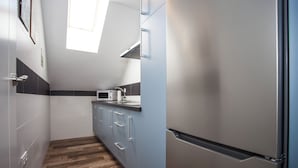 A narrow kitchen with a microwave, a refrigerator, and a window allowing natural light. - Apartamentos El Volante II (Ciempozuelos)