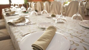 A table set for a formal event with white plates, folded napkins, and wine glasses. - Apartamentos El Volante II (Ciempozuelos)