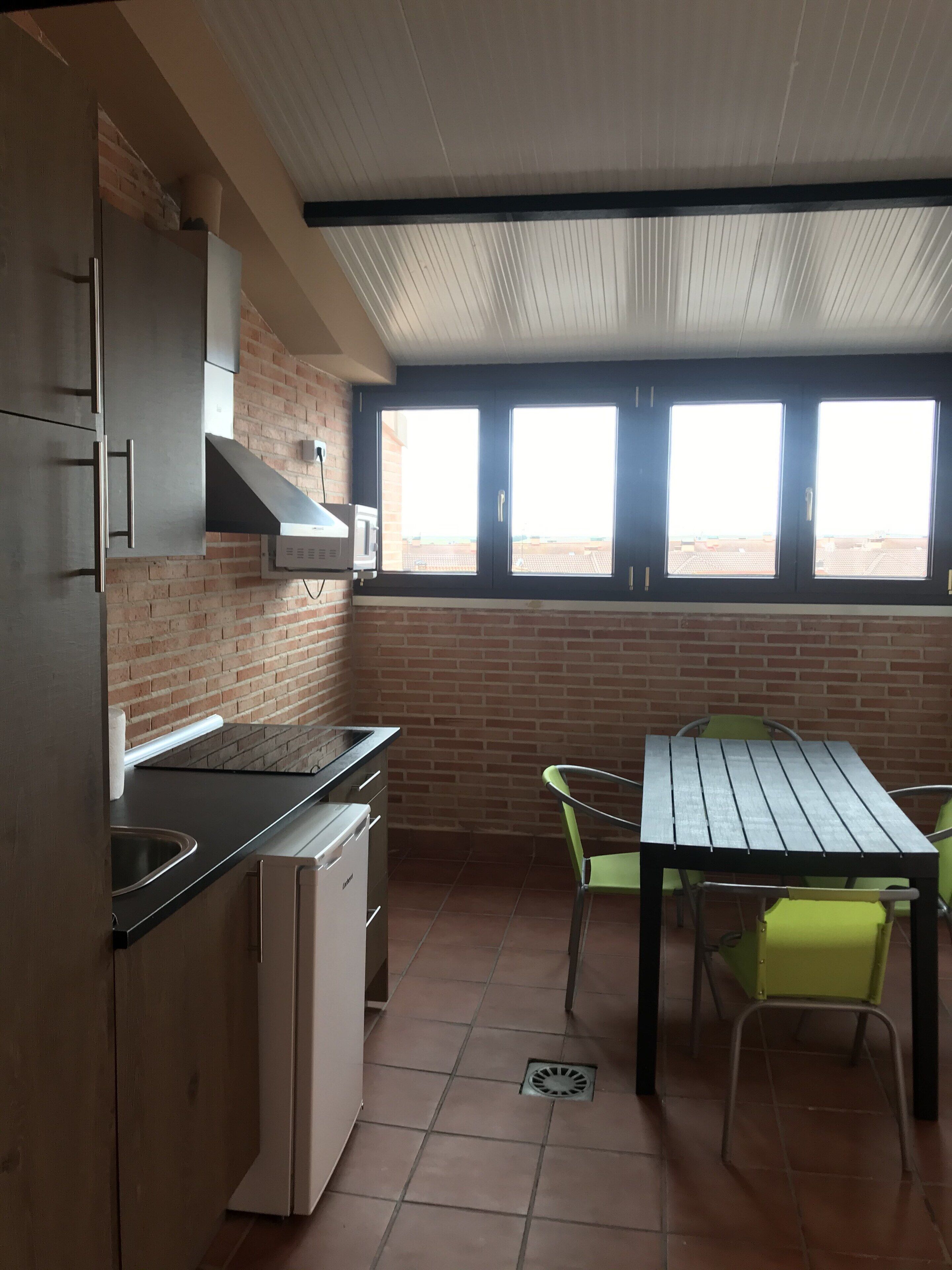 A kitchen with a brick wall, a window, and a table with chairs.
