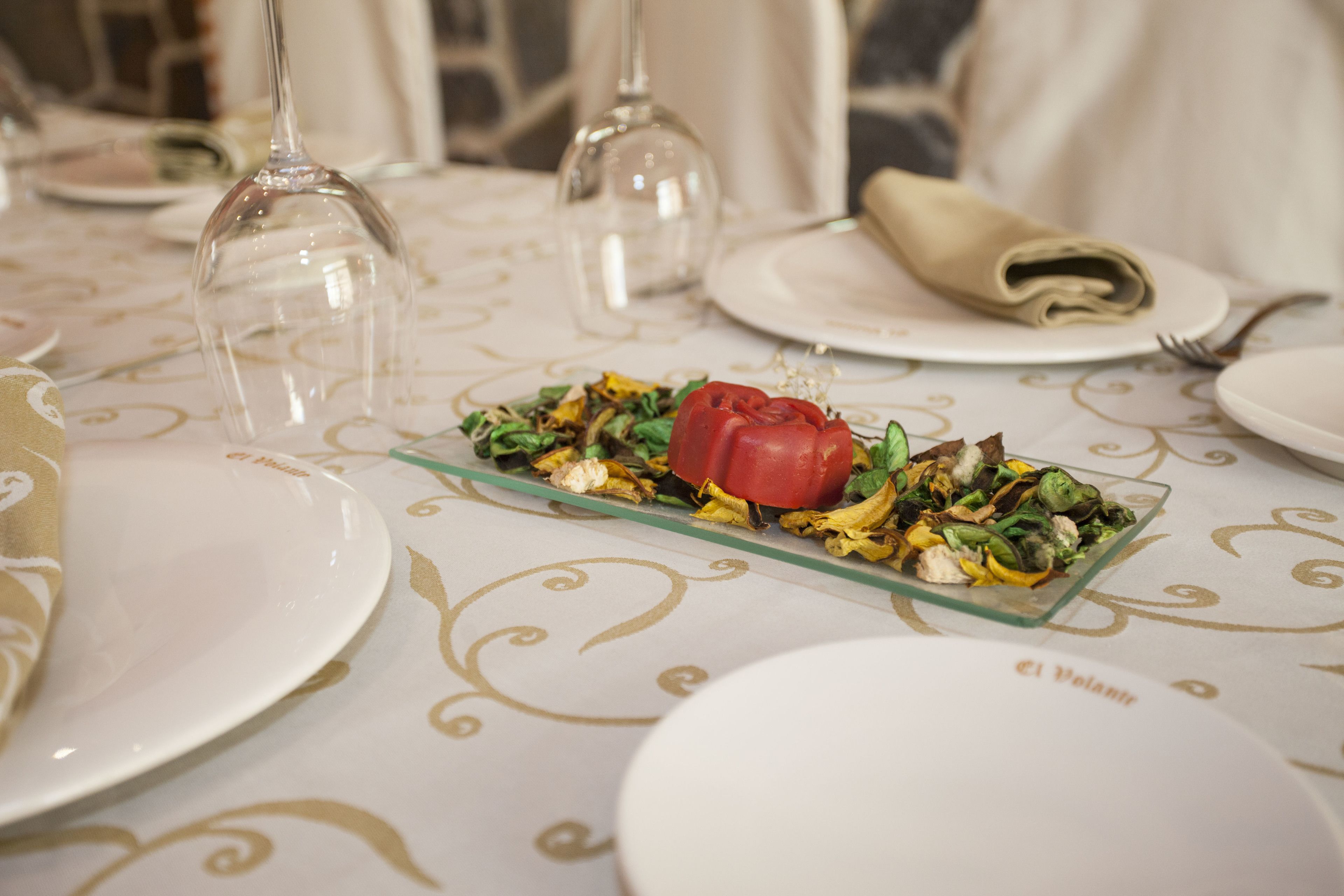 Una mesa de comedor dispuesta con platos, un bol de ensalada y copas de vino.