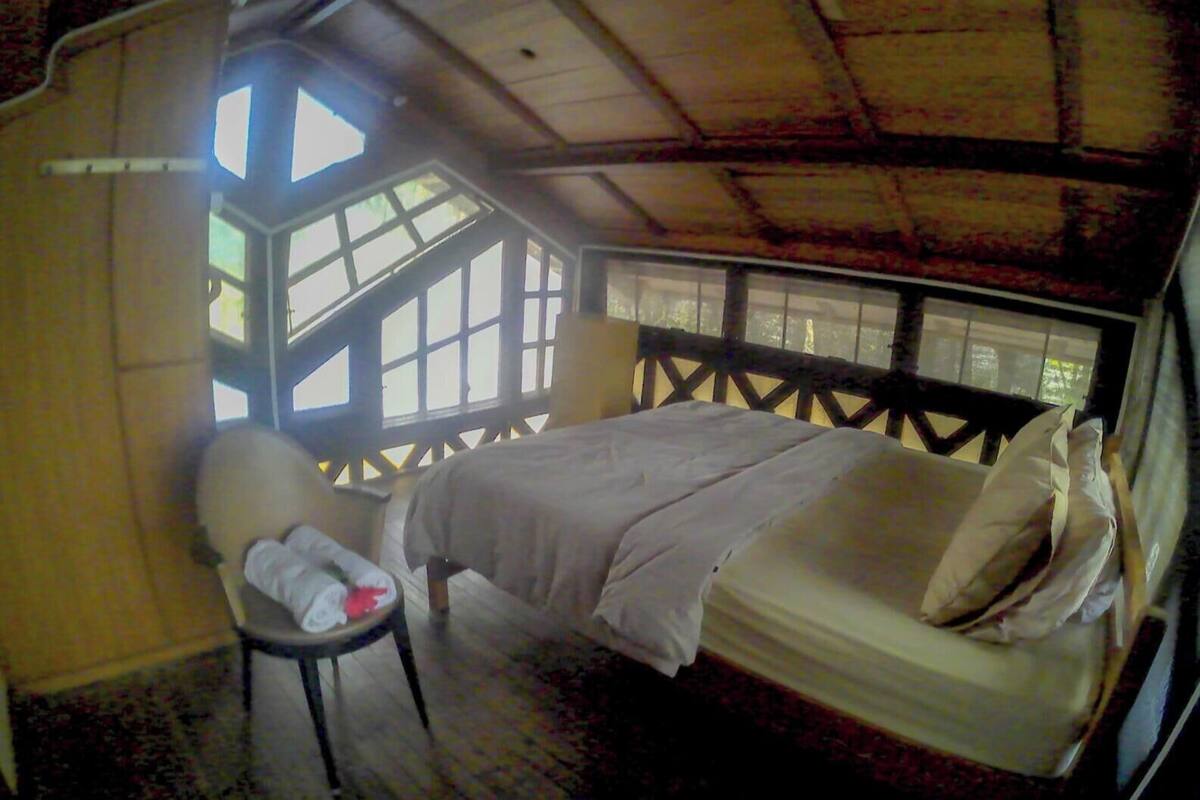 Una habitación con una cama, una silla y un ventanal.