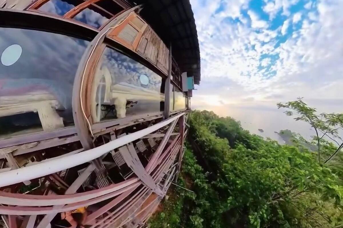Una estructura circular con armazón metálico y techo de madera, rodeada de abundante vegetación.
