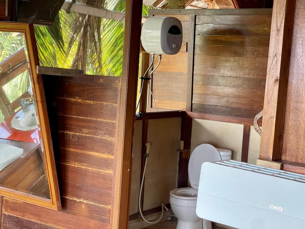 A compact bathroom with a toilet, a water heater, and a shower.